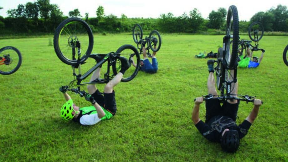 Mountainbiker*innen auf dem Rücken bei Fahrtechnik-Training auf der Wiese