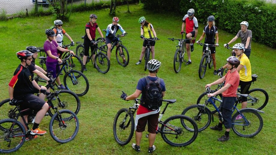 Mountainbiker*innen beim MTB-Kontroll-Check auf einer Wiese.