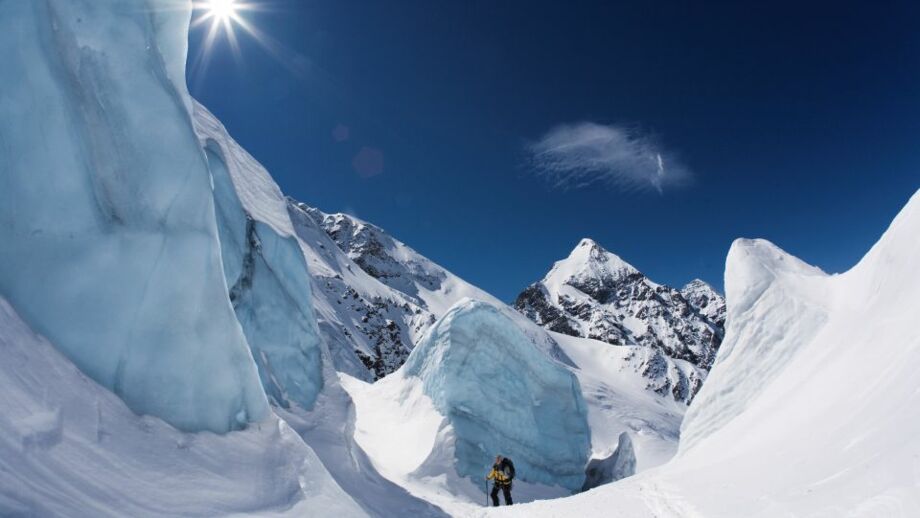 Skitourengeher im Aufstieg zwischen blauem Gletschereis