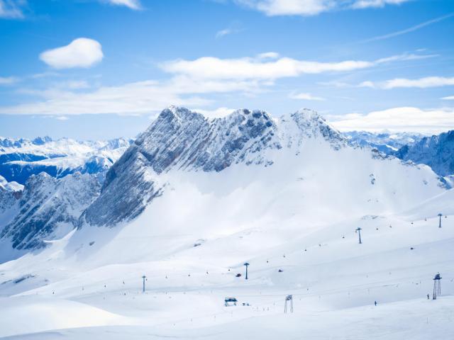 Verschneites Alpenpanorama und Skipiste im Vordergrund
