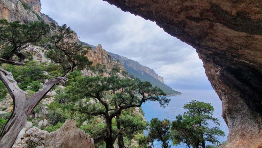 Blick aus einer kleinen Höhle in Richtung felsige Berge und das blaue Meer