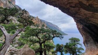 Blick aus einer kleinen Höhle in Richtung felsige Berge und das blaue Meer
