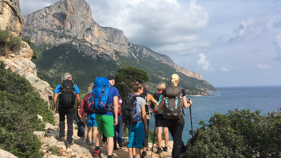 Wanderer an einem steinigen Hügel mit Blick auf das Meer und die Berge