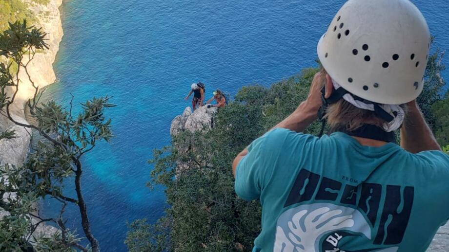 Wanderer an einer Klippe beim aufnehmen eines Fotos von zwei Wanderern auf der unteren Klippe, Ausblick auf das Meer