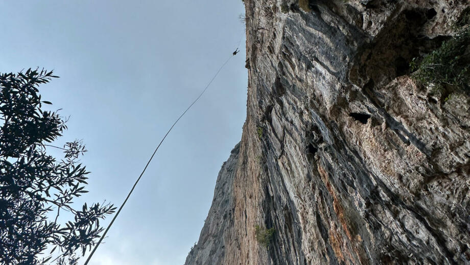 Wanderer beim Abseilen von einer sehr steilen und felsigen Klippe, Aufnahme von Unten