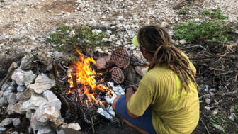 Guide der Gruppe am Lagerfeuer beim Würstchen grillen