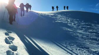 Neun bergsteiger*innen im aufstieg durch Schnee zum Gipfel des CSechstauswenders Chachacomani
