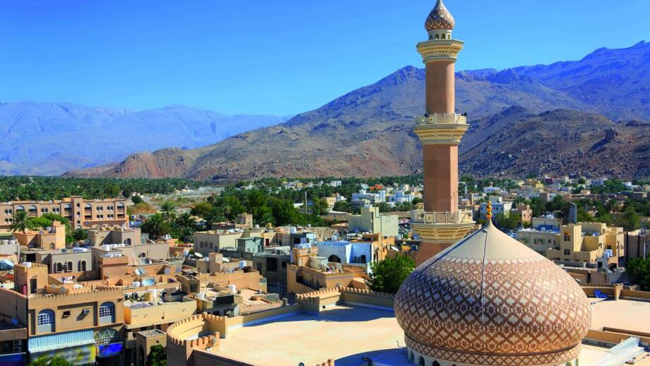 Bergstadt Nizwa im Oman mit Häusern, Moschee und Minarett und Bergen