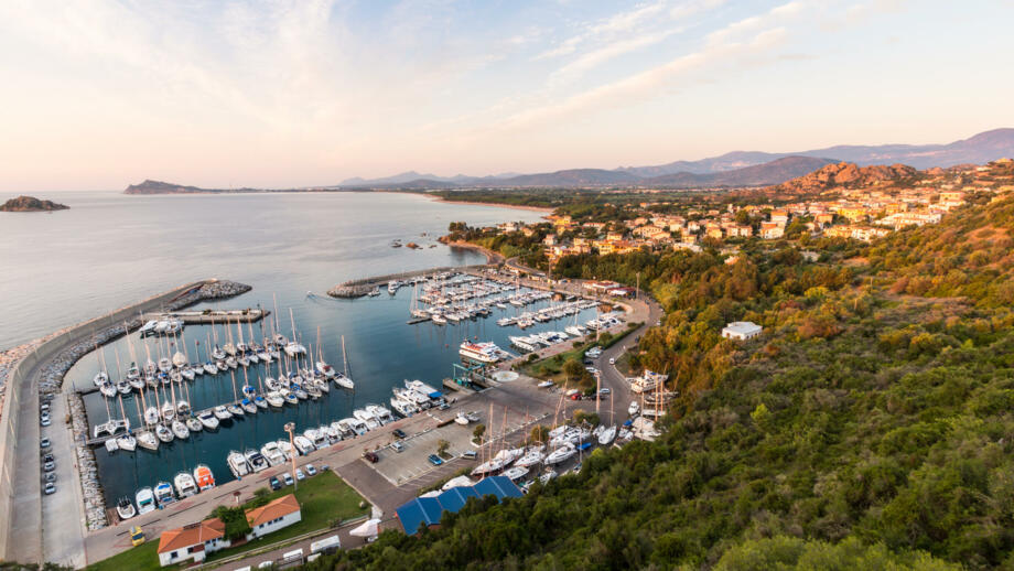 Der Hafen in Santa Maria Navaresse in Sardinien, viele Boote und Blick auf die Stadt bei Sonnenuntergang