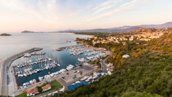 Der Hafen in Santa Maria Navaresse in Sardinien, viele Boote und Blick auf die Stadt bei Sonnenuntergang