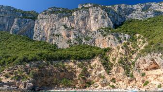 Panorama Aufnahme der stielen Klippen und der Kletterstege mit wenigen Bäumen, die Bucht von Cala Biriala,  die Küste von Orosei