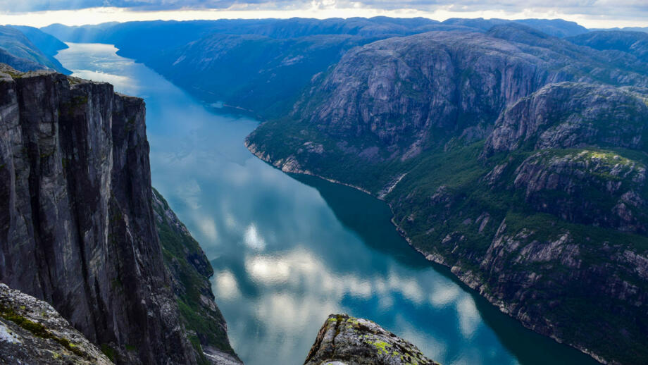 norwegen-nolys-berglandschaft-von-lysefjorden-mit-wolken-die-in-blauem-wasser-reflektiert-werden-blick-vom-kjerag-plateau-shutterstock_1735708061.jpg