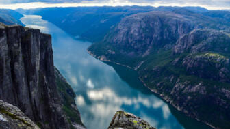 norwegen-nolys-berglandschaft-von-lysefjorden-mit-wolken-die-in-blauem-wasser-reflektiert-werden-blick-vom-kjerag-plateau-shutterstock_1735708061.jpg