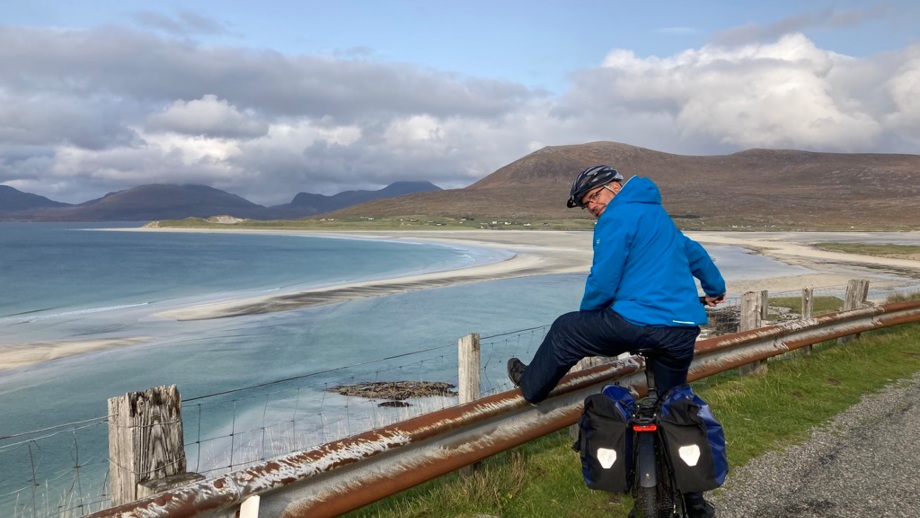 Eine Fahrradfahrerin während der Tour über die äußeren Hebriden in Schottland mit dem Meer im Hintergrund.