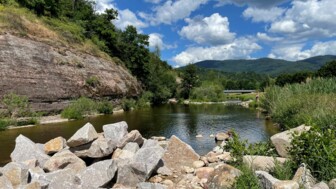 Der Fluss die Murg bei sonnigem Wetter mit den Wäldern des Schwarzwaldes im Hintergrund