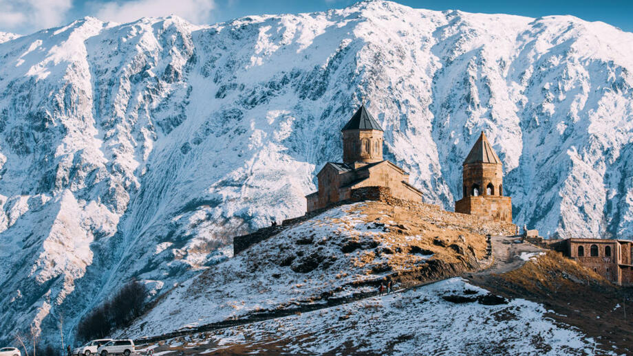 Wallfahrtskirche Gergeti vor den tiefverschneiten flanken des Fünftausenders Kasbek in Georgien