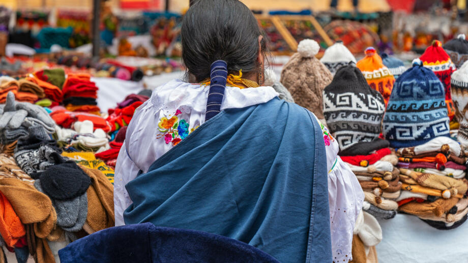 Eine einheimische Dame auf dem Markt in Quechua beim Verkaufen von Mützen, Handschuhen und Socken, Aufnahme von Hinten