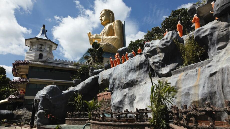 Mönche in orangen gewändern auf dem Weg zum vergoldeten Riesenbuddha in Dambulla, Sri Lanka
