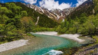 Azusa-Fluss im Kamikochi-Tal in den Japanischen Alpen mit Bäumen und Bergen im Hintergrund