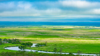 Fluss, grüne Wiesen und Meer im Kushiro-Shitsugen-Nationalpark auf der Insel Hokkaido