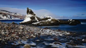 Küste des Ochotskischen meeres mit Felsen, Kieseln und etwas schnee auf der Insel Hokkaido