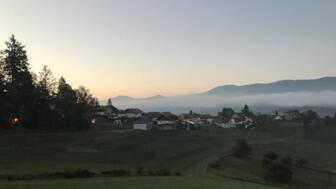 Der Sonnenuntergang über einer Wiese und den Wäldern des Bayrischen Walds.