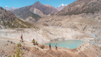 Eine Mountainbike Gruppe während einer Wanderung zur Akklimatiersierung. Ein See und das Annapurnagebirge im Hintergrund.