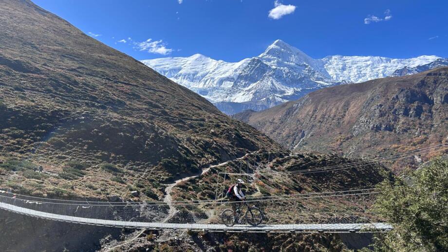 Ein Mountainbiker fährt über eine Brücke bei der Annapurna-Umrundung.