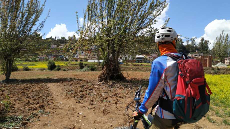 Ein Mountainbiker auf Tour im Kathmandu Tal. Im Hintergrund sind die Berge des Himalayas zu sehen.