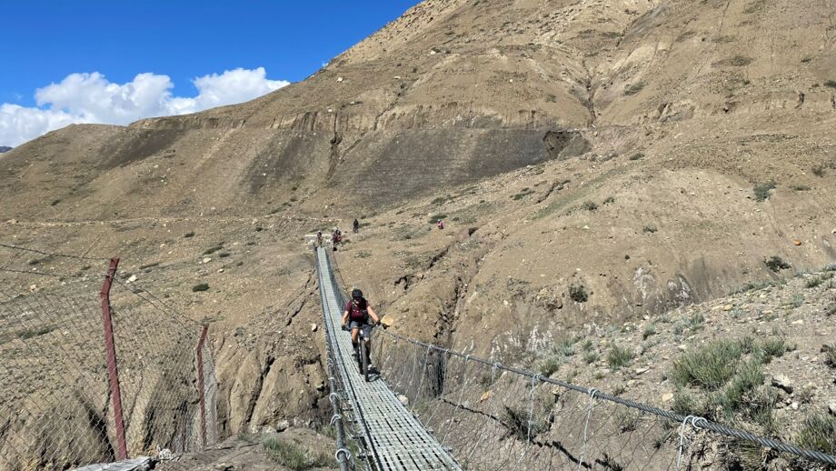 Ein Mountainbiker fährt über eine Hängebrücke in Nepal.