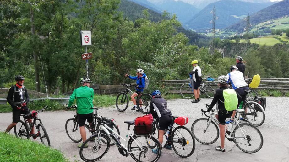 Eine Gruppe an Radfahrer*innen auf einer Straße stehend. Sie sind auf dem Weg nach Venedig.