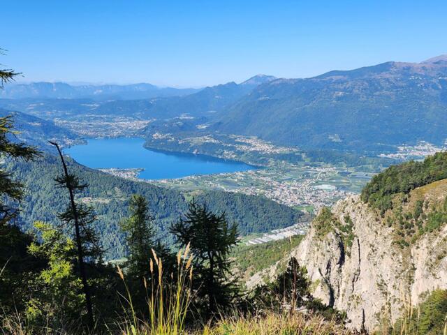 Der Blick auf den Levicosee von einem Berg. Die Sonne scheint. Der Himmel ist blau.