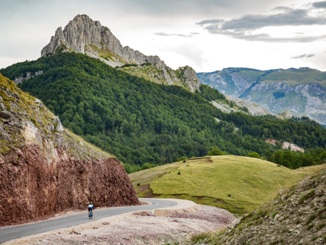 Ein Mountainbiker unterwegs durch die dinarischen Alpen. Im Hintergrund sind die Berge zu sehen.