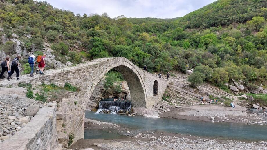 Eine Wandergruppe überquert eine Steinbrücke im Süden Albaniens