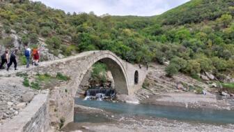Eine Wandergruppe überquert eine Steinbrücke im Süden Albaniens