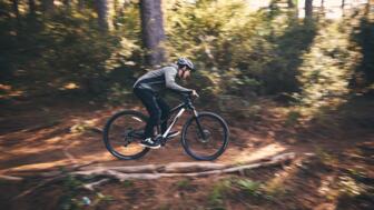 Ein Mountainbiker unterwegs im Wald auf einem Trail beim Fahrtechniktraining.