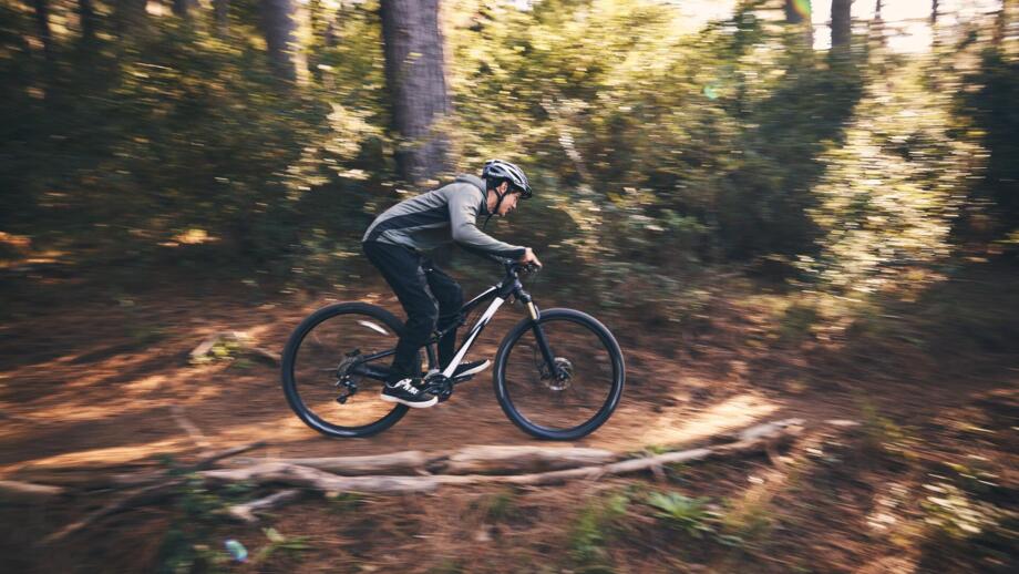 Ein Mountainbiker im Wald auf einem Trail während des Fahrtechniktrainings.
