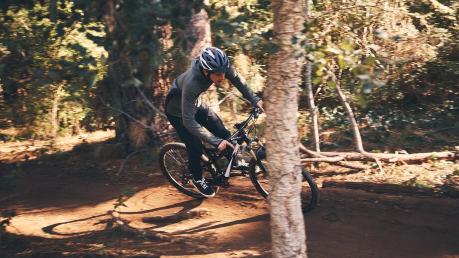 Ein Mountainbiker im Wald auf einem Trail während des Fahrtechniktrainings.