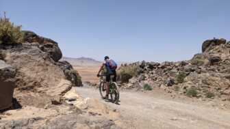 Eine Mountainbikerin ist unterwegs im Atlasgebirge. Im Hintergrund sieht man die Berge.