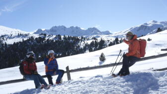 Skitourengruppe macht eine Pause im Winterlandschaft mit Sonne und blauem Himmel