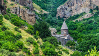 Weltkulturerbe Kloster Geghard in einem grünen und von Felsen gerahmten Tal