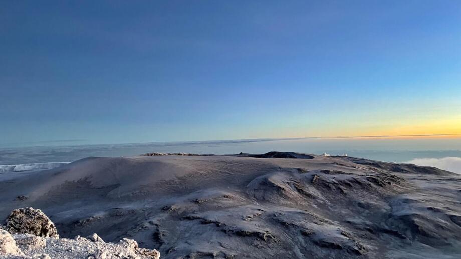 Blick vom Gipfel des Kilimandscharo auf die davorliegenden Gletscher und dem Sonnenaufgang dahinter