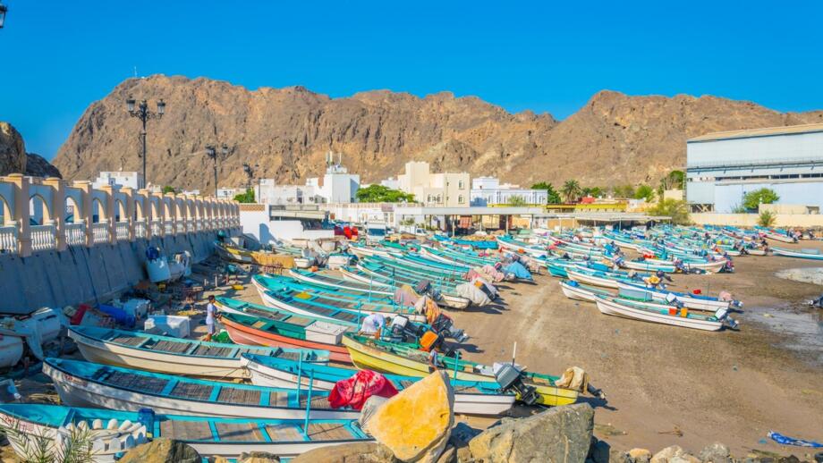 Bunte Fischerboote am Sandstrand vor Felskulisse