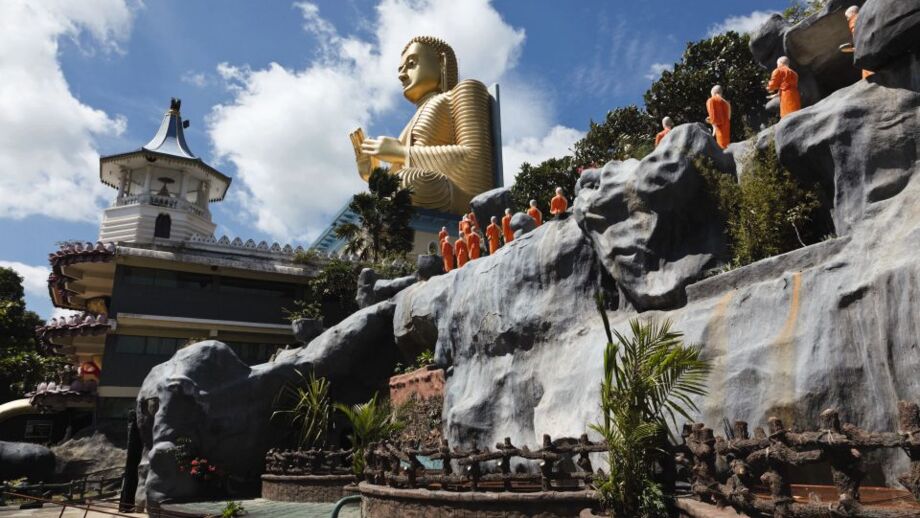 Mönche in orangen gewändern auf dem Weg zum vergoldeten Riesenbuddha in Dambulla, Sri Lanka