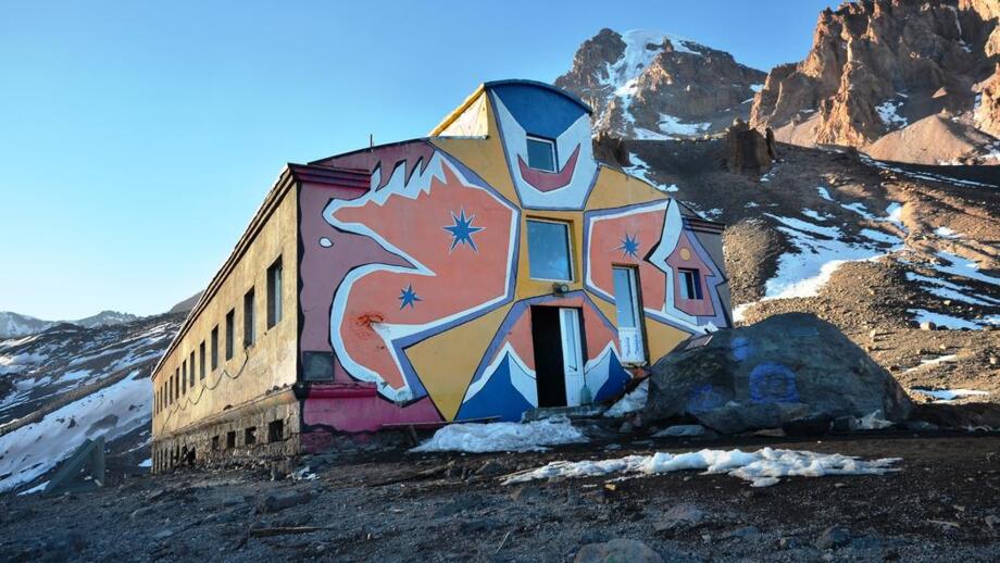 Bunt bemalte Bethlemi-Hütte am Fünftausener Kasbek in Georgien mit Felsen, Schotter und Schneeresten