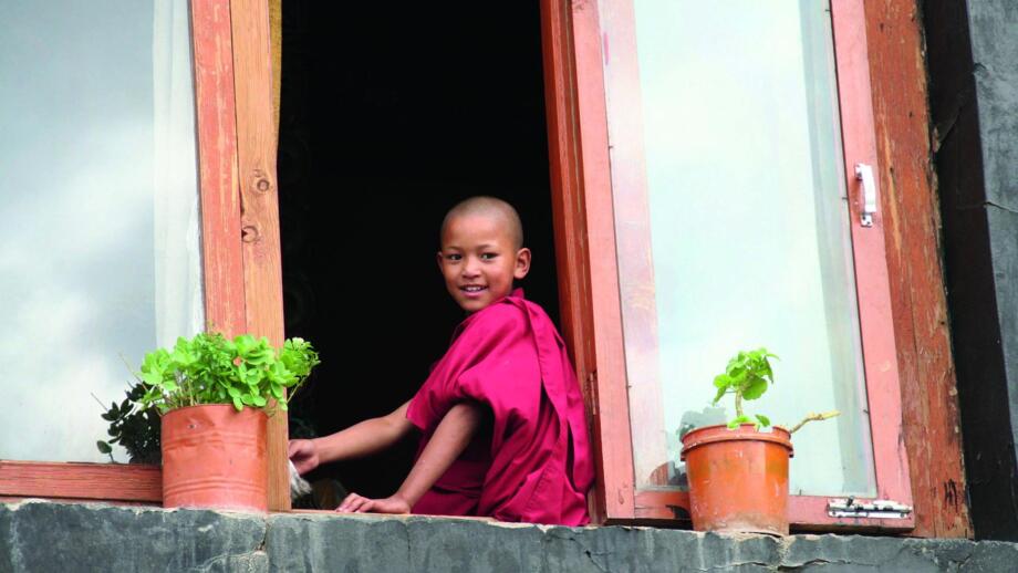 Junger Mönche sitzt auf einem Fenstersims in Ladakh