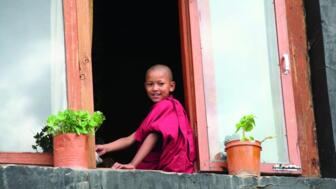 Junger Mönche sitzt auf einem Fenstersims in Ladakh