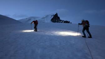 Seilschaft mit Stirnlampen am Gletscher unterwegs