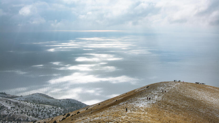 Wanderer im Abstieg vom Berg Artanish mit Blick auf den tief unten liegenden Sevansee