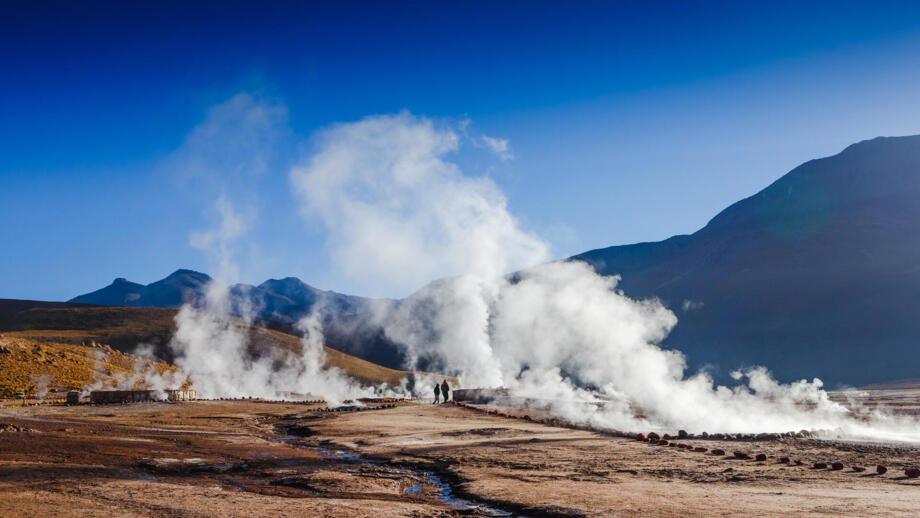 Besucher vor dampfenden Geysiren auf dem Vulkanfeld El Tatio am Rande der Atacama-Wüste in Chile